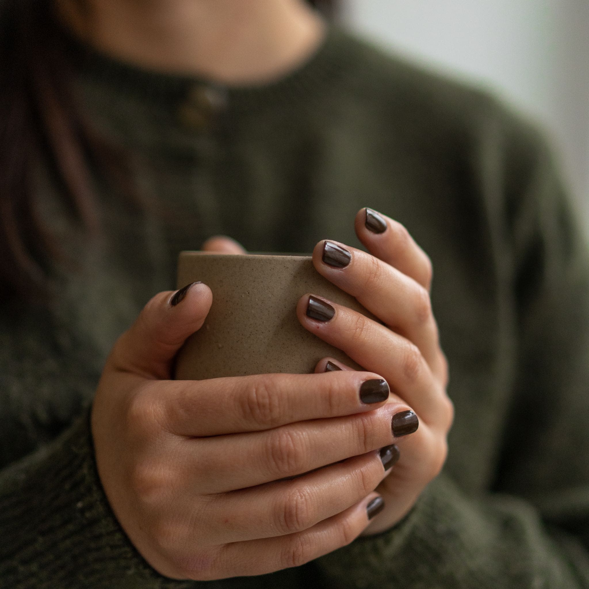 main femme avec vernis marron faux ongles